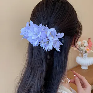 Detail view of a purple fabric flower hair clip styled on long dark hair in a warm setting