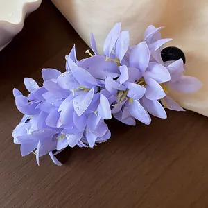 Close-up of delicate purple fabric flower hair clip with realistic dewdrop details.