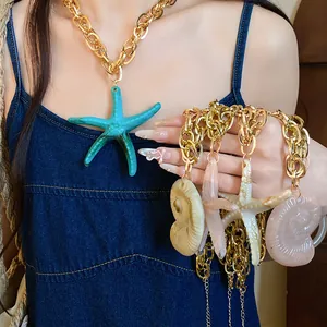 Close-up detail of acrylic starfish and shell pendants on a chunky vintage gold chain necklace.