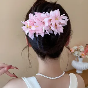 A sweet pink fabric flower hair clip showcased on an elegant updo for a vacation look