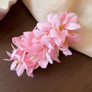 Detailed view of pink fabric flower hair clip with sparkling dewdrop accents on petals.