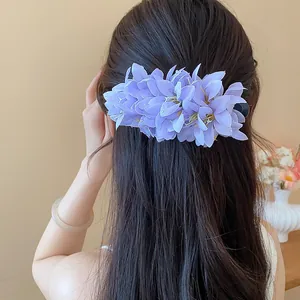 Close-up detail of a purple fabric flower duckbill hair clip worn on long dark hair