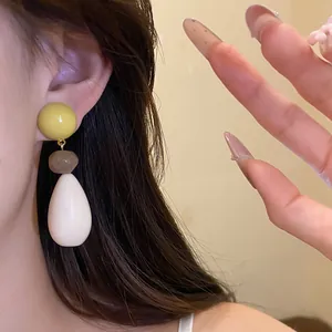 Close-up of elegant resin water-drop earrings worn on ear, showing a stylish retro design.