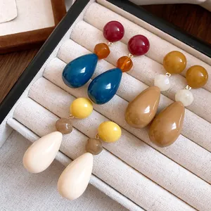 Close-up of vintage resin teardrop earrings in various colors displayed in a jewelry tray