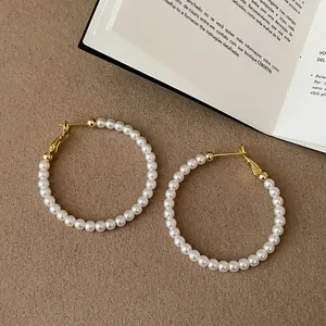 Eleganti orecchini a cerchio di perle con accenti dorati su superficie testurizzata.