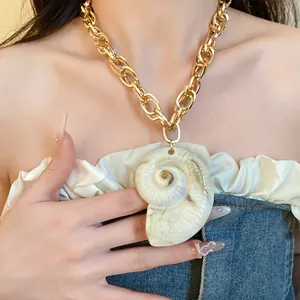 Close-up of vintage acrylic spiral conch pendant on a chunky gold link chain necklace
