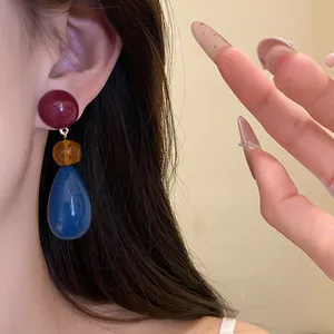 Close-up of retro resin water drop pendant earrings worn on the ear
