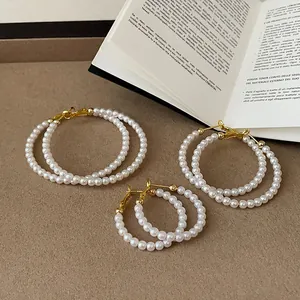 Set di tre paia di eleganti orecchini a cerchio con perle su uno sfondo strutturato