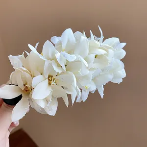 Detailed macro view of delicate white cloth flower hair clip with water droplets