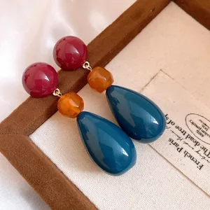 Detailed view of retro resin teardrop earrings with red, amber, and blue color blocking.