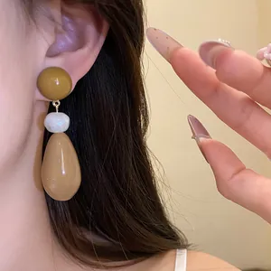 Detail view of vintage resin waterdrop pendant earrings worn on an elegant model's ear