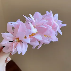 Close-up detail of a delicate pink fabric simulation flower hair clip with dew-like beads