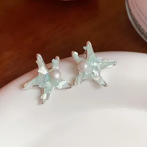 Detailed macro view of starfish stud earrings with a pearl center and iridescent shell inlay