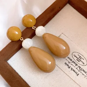 Detailed view of vintage resin water-drop earrings in warm amber and white tones.