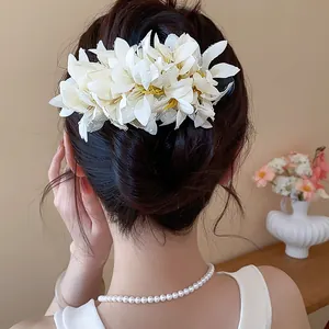 Detail view of a large white fabric flower hair clip styled on an elegant updo hairstyle.