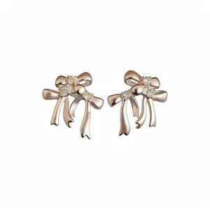 Élégantes boucles d'oreilles en forme de nœud en or rose avec zircons sur fond blanc