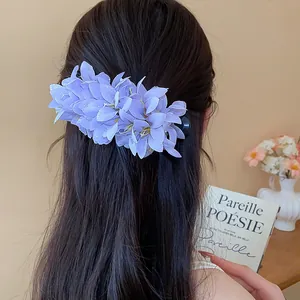 Elegant purple fabric flower hair clip on long hair for a sweet holiday look