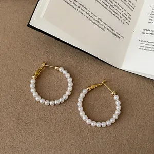 Dettaglio ravvicinato di eleganti orecchini a cerchio con perle e accenti dorati raffinati