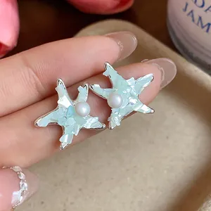Detail view showing elegant starfish stud earrings with pearl and crushed shell inlay