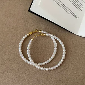 Dettaglio di eleganti orecchini a cerchio con perle e ganci dorati lucidi