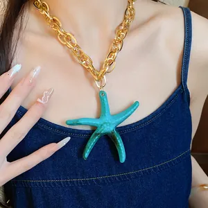 Detailed shot of a vibrant turquoise acrylic starfish pendant on a chunky gold chain