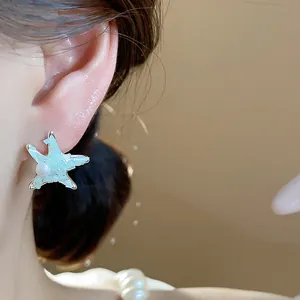 Close-up of light blue starfish pearl stud earrings worn for elegant resort style