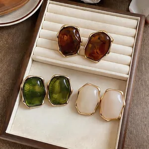 Vintage resin oval stud earrings with gold-plated trim in amber green and white colors