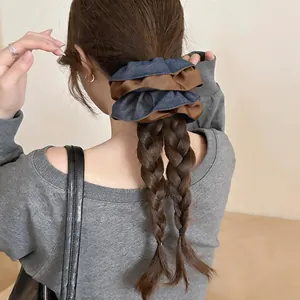Detail view of a large blue and brown two-tone fabric scrunchie on double braided hair