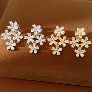Close-up of elegant flower ear clips set with cubic zirconia in gold and silver.