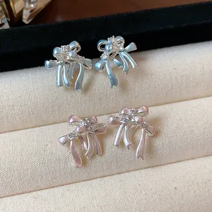 Gros plan détaillé de boucles d'oreilles nœuds élégantes en rose et bleu avec des zircons