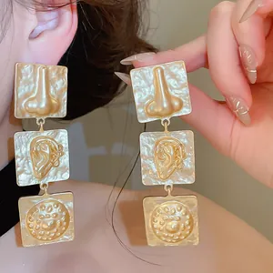 Close-up of unique vintage gold statement earrings with geometric facial feature patterns