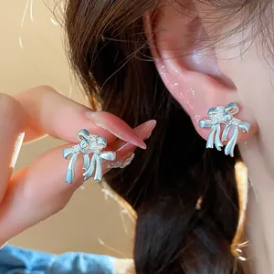 Gros plan détaillé d'une boucle d'oreille nœud en argent sertie de zircons étincelants.