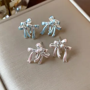 Élégantes boucles d'oreilles nœud avec zircons brillants en bleu clair et rose pastel.