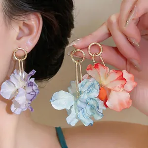 Detail of oversized fabric flower earrings in vibrant colors for a vacation look.