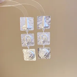 Silver geometric earrings featuring unique embossed nose and ear facial motifs