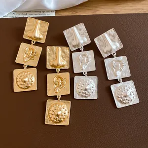 Detailed view of matte gold and silver earrings with geometric nose and ear designs.