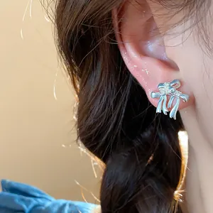 Vue détaillée de boucles d'oreilles nœud en argent avec zircons portées par un modèle