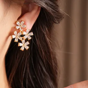 Detail shot of sparkling zircon flower ear clips in a gold-plated finish on a model.