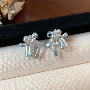 Vue détaillée des boucles d'oreilles nœud bleu clair avec pierres en zircone et tiges en argent