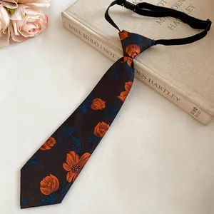 Detailed view of vintage handmade floral embroidered tie necklace on an antique book