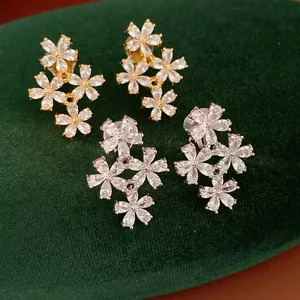 Detailed view of sparkling cubic zirconia flower ear clips on green velvet background