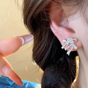 Gros plan d'une boucle d'oreille nœud en argent avec zircons sur l'oreille