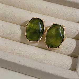 Macro shot of green resin earrings with elegant gold irregular edges in a jewelry box