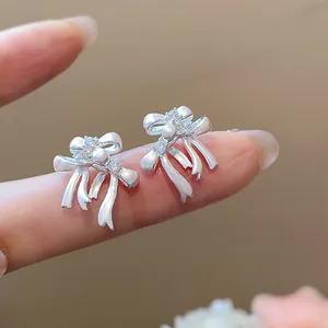 Détail de boucles d'oreilles nœud délicates en argent avec accents de zircon et perles