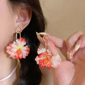 Macro detail of vibrant fabric flower drop earrings featuring elegant gold-tone rings