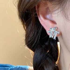 Détail d'une boucle d'oreille nœud en argent avec zircons étincelants sur l'oreille du mannequin