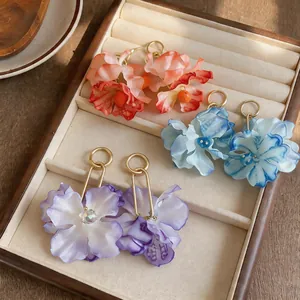 Close-up detail of elegant fabric flower earrings in various colors within a display tray