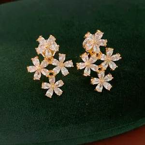 Close-up of elegant flower-shaped ear clips with sparkling cubic zirconia in 18K gold plating.