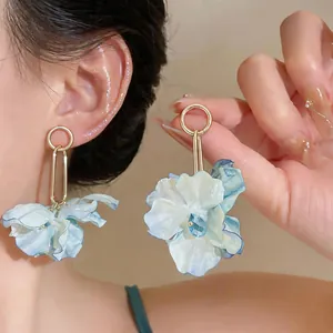 Close-up detail view of light blue fabric flower earrings with crystal drop on model