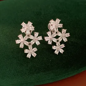 Detailed view of silver flower clip-on earrings with zircon stones on green velvet